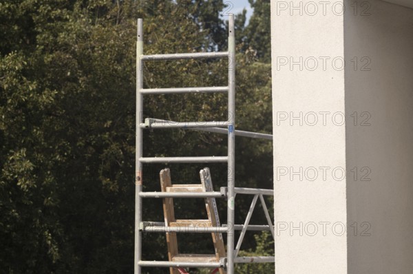 Borken, NRW, Germany, Scaffolding frame with wooden ladder against a building exterior and green