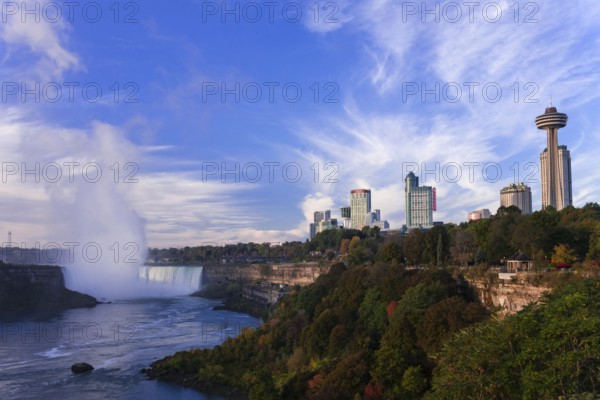 Skyline with prominent tower and the Horseshoe Falls under a bright blue sky in Niagara Falls,