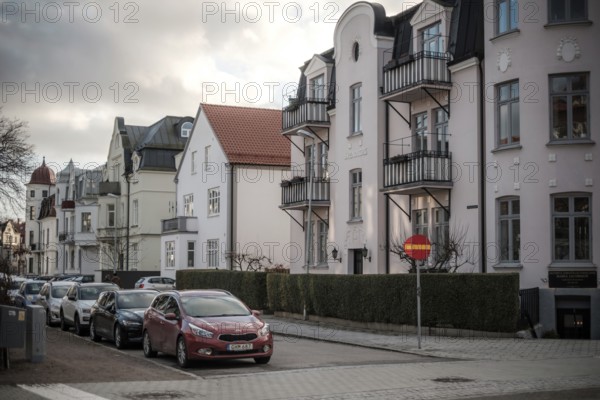 Street view of European residential buildings with parked cars and a cloudy sky in Helsingborg,