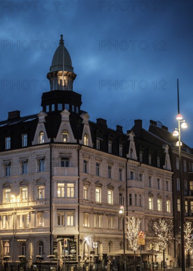 An elegant historic building with illuminated windows against a blue evening sky in Helsingborg,