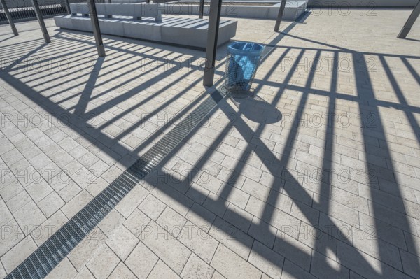 Concrete pavement, blue rubbish bin, long shadows at the state vocational school, Kempten, Allgäu,