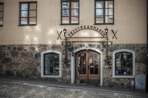 Charming building with a stone wall and decorative entrance on cobblestone street in Helsingborg,