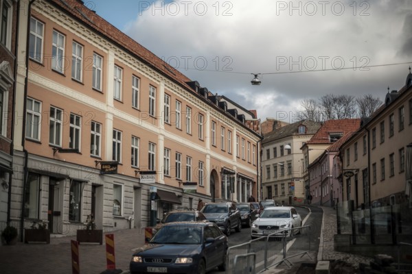 City street with parked cars and pastel-colored buildings under a cloudy sky in Helsingborg,