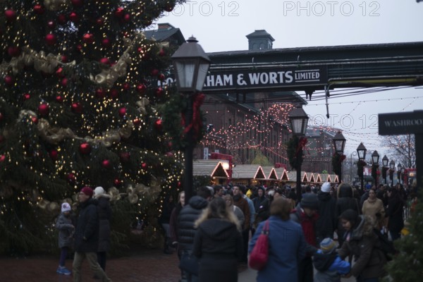 A bustling outdoor Christmas market at the Gooderham and Worts Distillery District, with festive