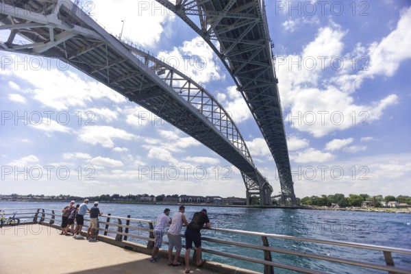 People enjoying the river view underneath the Blue Water Bridge, connecting Canada to the United