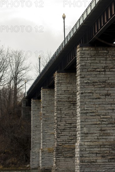 Image of a bridge with massive stone columns under an overcast sky, creating a somber industrial