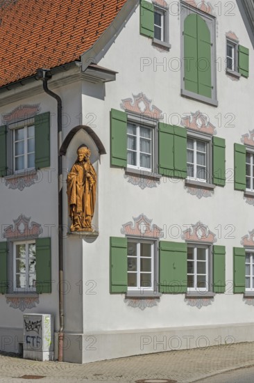 Blue sky, pointed gable house with green shutters and bishop figure, Kisslegg, Allgäu,