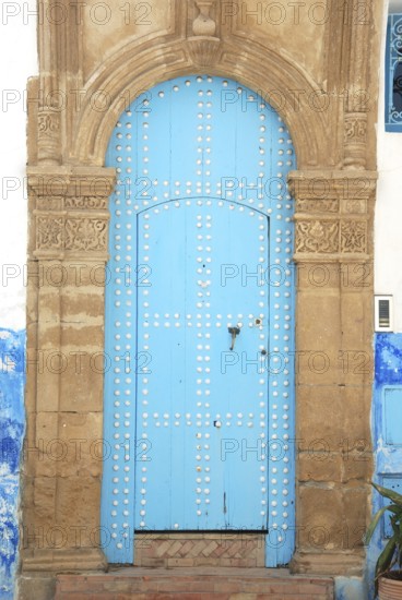 An ancient blue door with an ornate stone archway, featuring a weathered look in a historical
