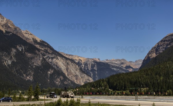 Mountain pass with highway and vehicles, surrounded by forest as viewed from the Trans Canada