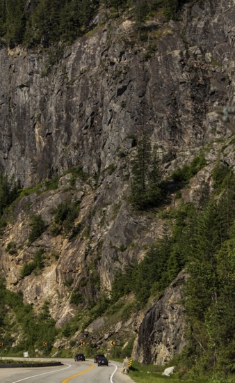 Winding road through a rugged mountainous area with dense forest in Revelstoke, British Columbia,