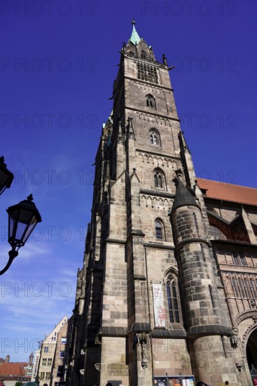 Gothic church tower made of sandstone, rises in front of a bright blue sky, Church of St. Lawrence,