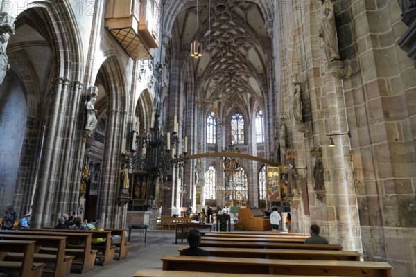Large church room with pews and Gothic architecture, visited by people, Church of St. Lawrence,