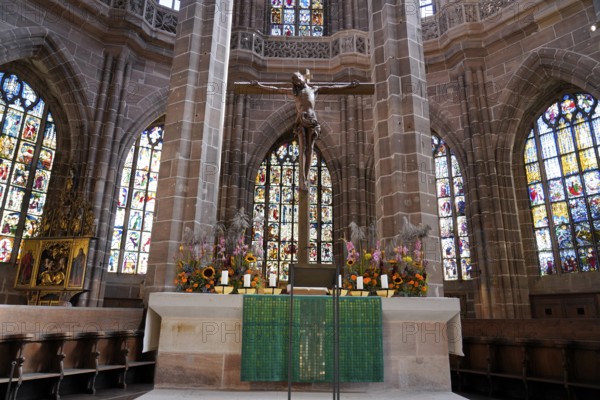 Church altar with cross and colourful stained glass windows depicting biblical scenes, St. Lawrence
