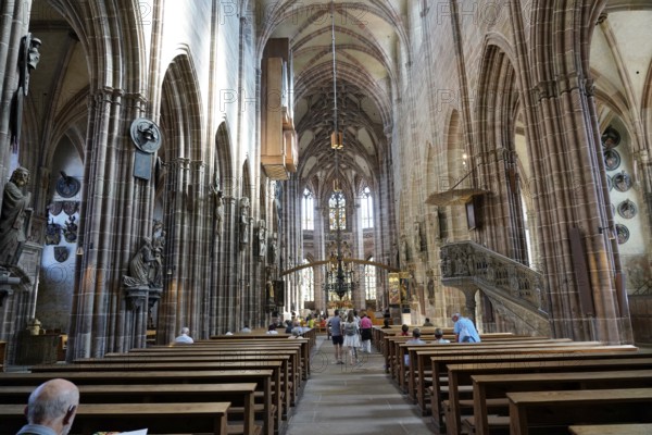 Nave with high vaults, benches and people inside a historic church, Church of St. Lawrence,