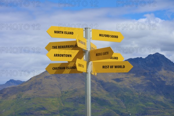 Yellow signpost in a mountain landscape, showing directions to different places, Queenstown,