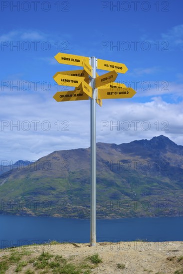 A signpost on a hill shows yellow signs in different directions, Queenstown, Queenstown-Lakes