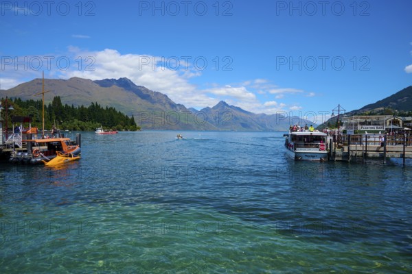 Boats on a jetty with a view of the surrounding mountains and blue water, Queenstown,
