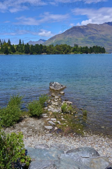 Rocks on the shore of a lake with mountains in the background and a clear atmosphere, Queenstown,