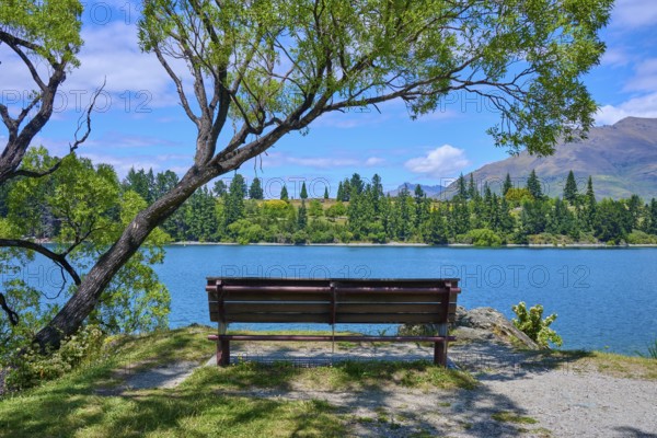 Idyllic landscape with bench and view of a lake and mountains in the background, Queenstown,