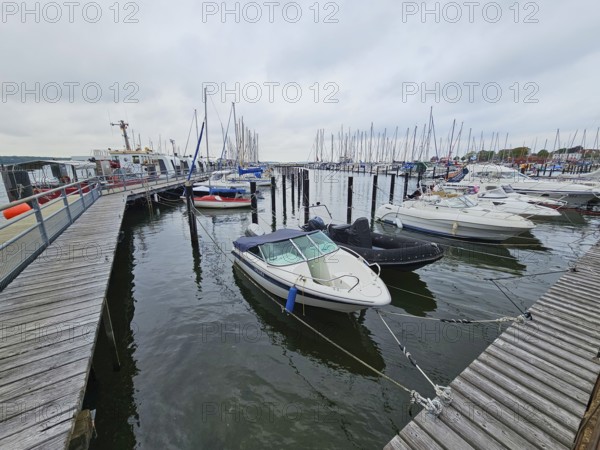 Several motorboats are moored in a harbour, surrounded by jetties and under an overcast sky, Laboe,
