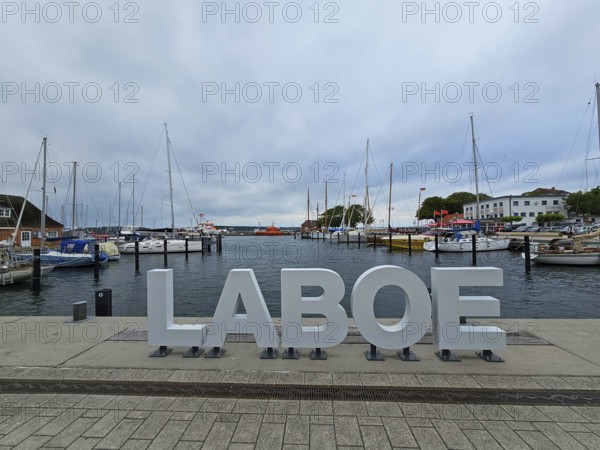 LABOE lettering at the edge of the harbour, surrounded by sailing boats and a cloudy sky, Laboe,