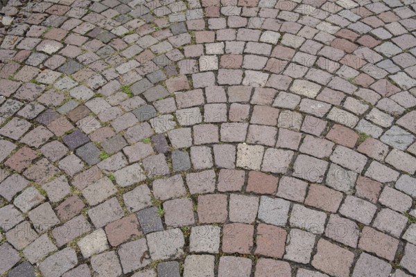 Floor covering made of paving stones with an arched pattern in grey and reddish tones, background,