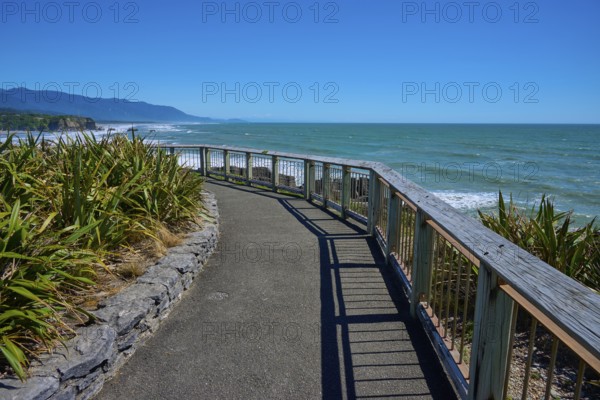 A walkway with railings offers a wide view over the sea and the coastline, Pancake Rocks, Westport,