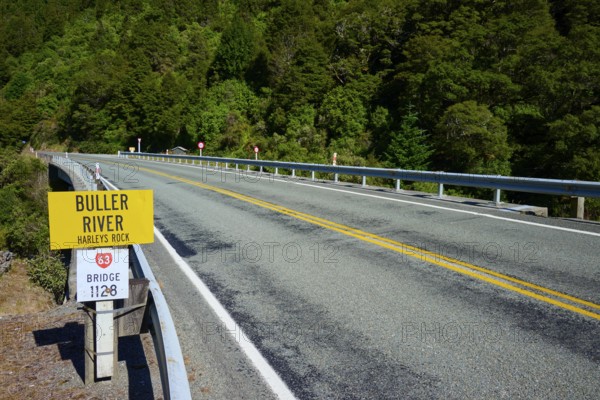 Road leads over bridge at Buller River, surrounded by forest and traffic signs, Buller River,