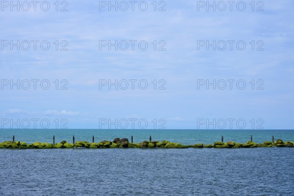 View of the sea with a row of rocks and calm blue sky, Mana Bay, Patea, Taranaki, North Island, New