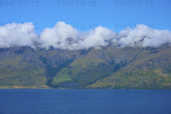 Mountains with a wreath of clouds over a blue lake under a clear sky, Drift Bay, Lake Wakatipu,