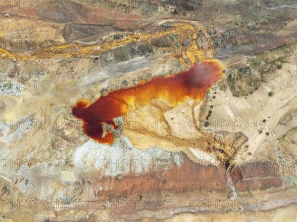 Old mining site and deep orange-red hues in the water of a pool in the mineral-rich area of the Rio