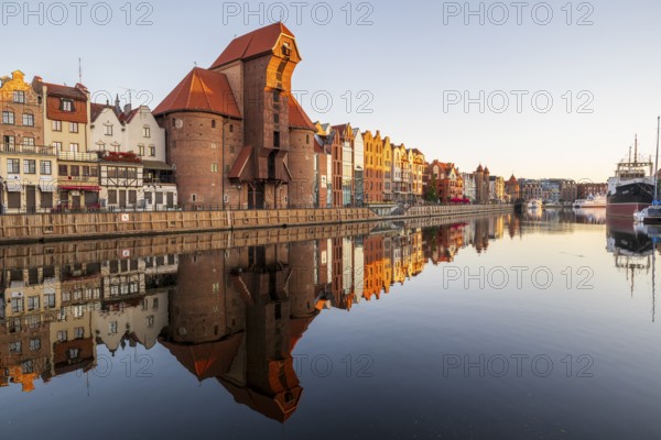 Waterfront promenade with reflection at sunrise in the Old Town, Brama Zuraw crane gate, Motlawa