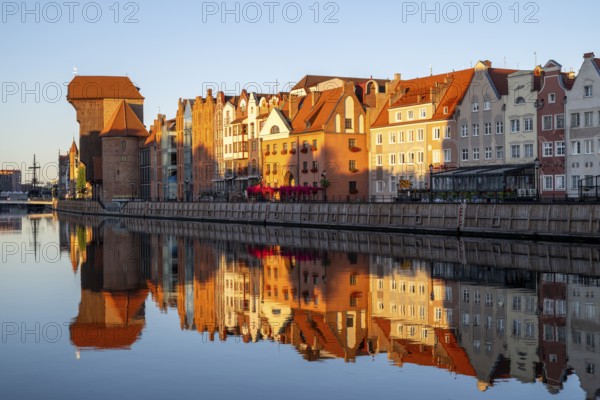 Waterfront promenade with reflection at sunrise in the Old Town, Brama Zuraw crane gate, Motlawa