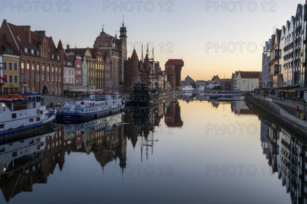 Waterfront promenade with reflection at sunrise in the Old Town, Brama Zuraw crane gate, Motlawa
