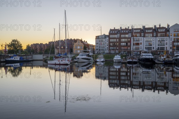 Waterfront promenade with reflection at sunrise in the old town, Motlawa river, boat harbour,