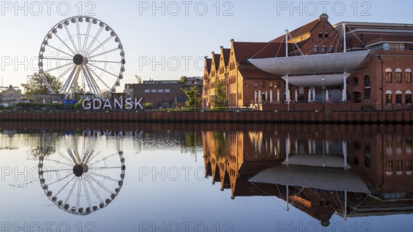 Ferris wheel on the waterfront with reflection at sunrise in the old town, Motlawa River, Gdansk,