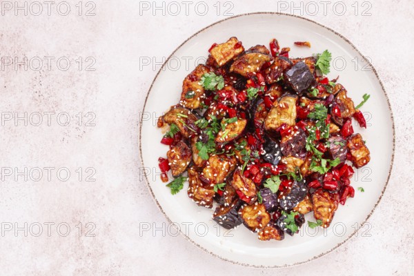 Fried eggplant, Chinese style, in sweet and sour sauce, with pepper and sesame seeds. on a white
