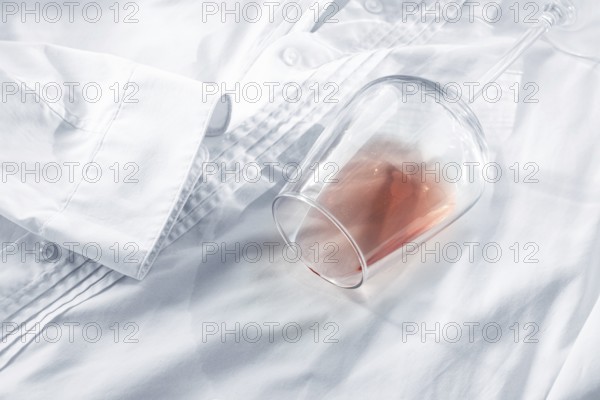Glass, with pink wine, spilled on a white shirt, close-up, selective focus, no people, concept, top