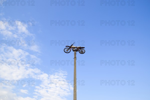 Motorcycle on the pedestal. A light motorbike on a pole, put up as a dummy or a monument.