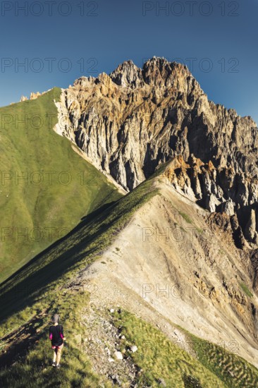 Hiker walking along narrow ridge trail at Kabarjina Mountain in Kazbegi National Park Georgia with