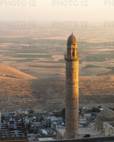 Historic Ulu Cami minaret in Mardin Turkey illuminated by sunset, overlooking ancient Mesopotamian