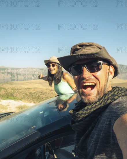 Happy travelers on summer road trip with rental car, symbolizing freedom, travel insurance, car