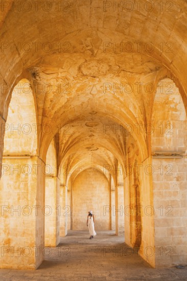 Kasimiye Medrese stone arches with traveler in white dress, iconic historic landmark in Mardin,