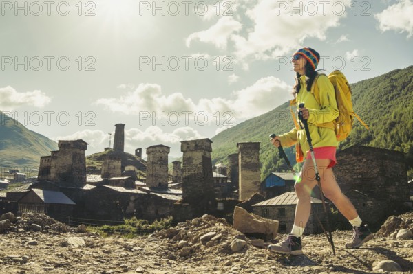 Traveler hiking with backpack and poles in Ushguli, Svaneti mountains, wellness trekking and