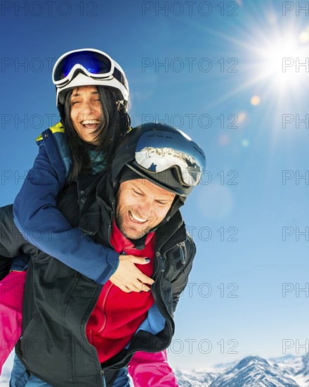 Romantic happy skiers couple in love having fun together playing in mountains piggybacking at