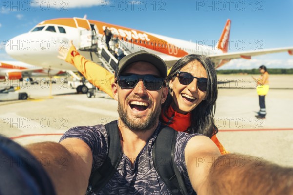 Milan, Italy - 12th august, 2025: happy smiling couple taking selfie in front of EasyJet airplane
