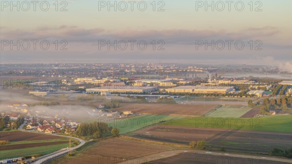 An extensive industrial area becomes visible in the morning sun. Fog envelops the landscape and the
