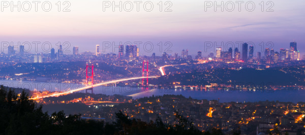 View from Camlica hill to 15 July Martyrs bridge with scyscrapers in the background after sunset
