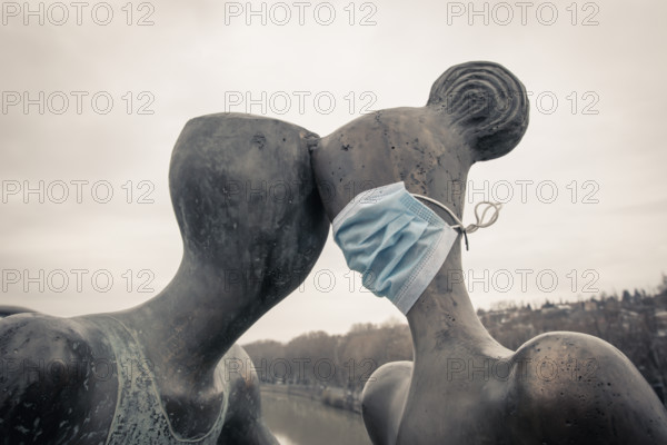 Statue of a couple with medical mask on. Concept of relationship and social distance during