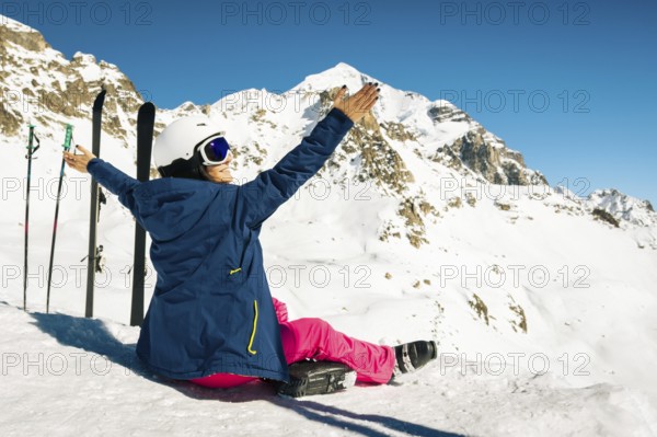 Young happy caucasian woman pose with skis arms outstretched in alpine zone. Get away skiing